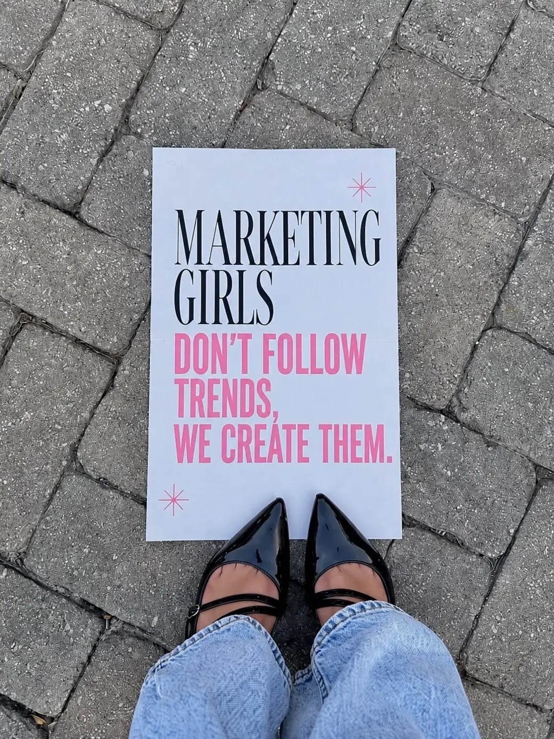 Angela holding a poster that reads ‘Marketing girls don’t follow trends, we create them’